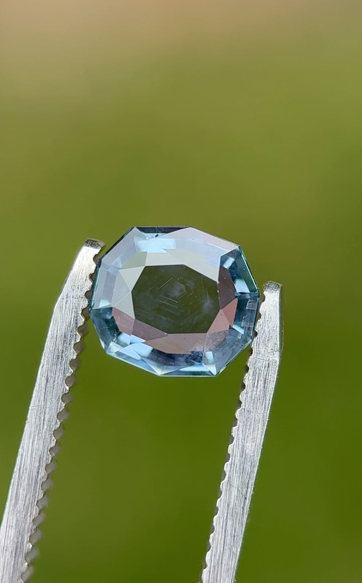 360-degree video of a 2.08-carat color-shift Montana sapphire in tweezers, showcasing the custom cushion tablet cut and blue-violet shift.