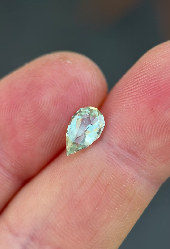 1.43ct light seafoam green sapphire rotating in hand, revealing soft mint and aqua flashes across the precision pear cut.