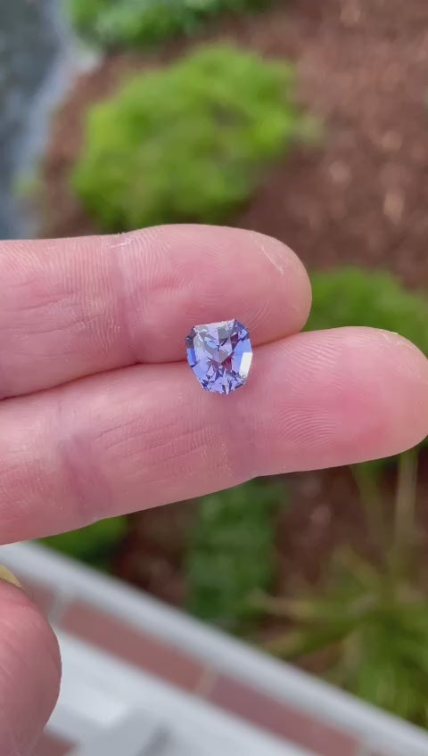 Close-up video of a Tanzanite gemstone from Merelani Hills, Tanzania, rotating to highlight its intricate geometric shield cut and the vivid interplay of blue, purple, and lavender hues.