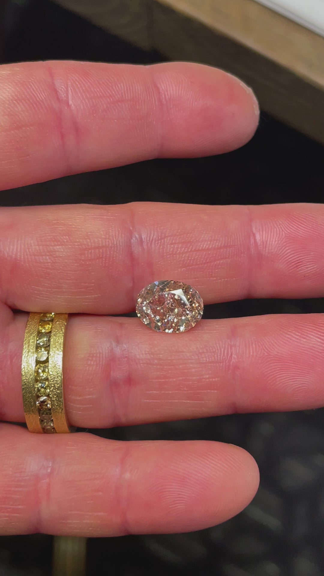 Handheld video of a 5.25-carat oval diamond under natural light, capturing its warm champagne hue and strong fluorescence, enhancing its brilliance.