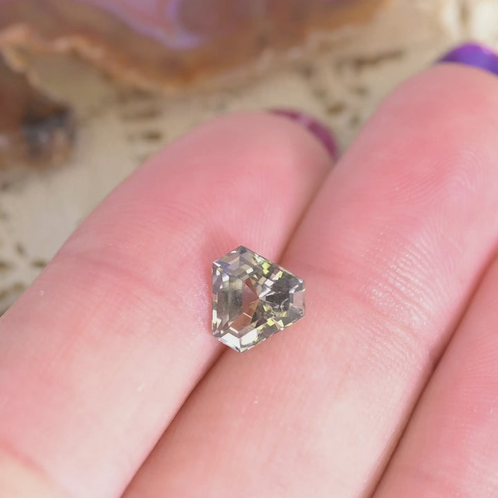 1.87 carat custom calf head step cut Tanzanite rotating under light showing fancy peach lavender color play and sparkle from Tanzania