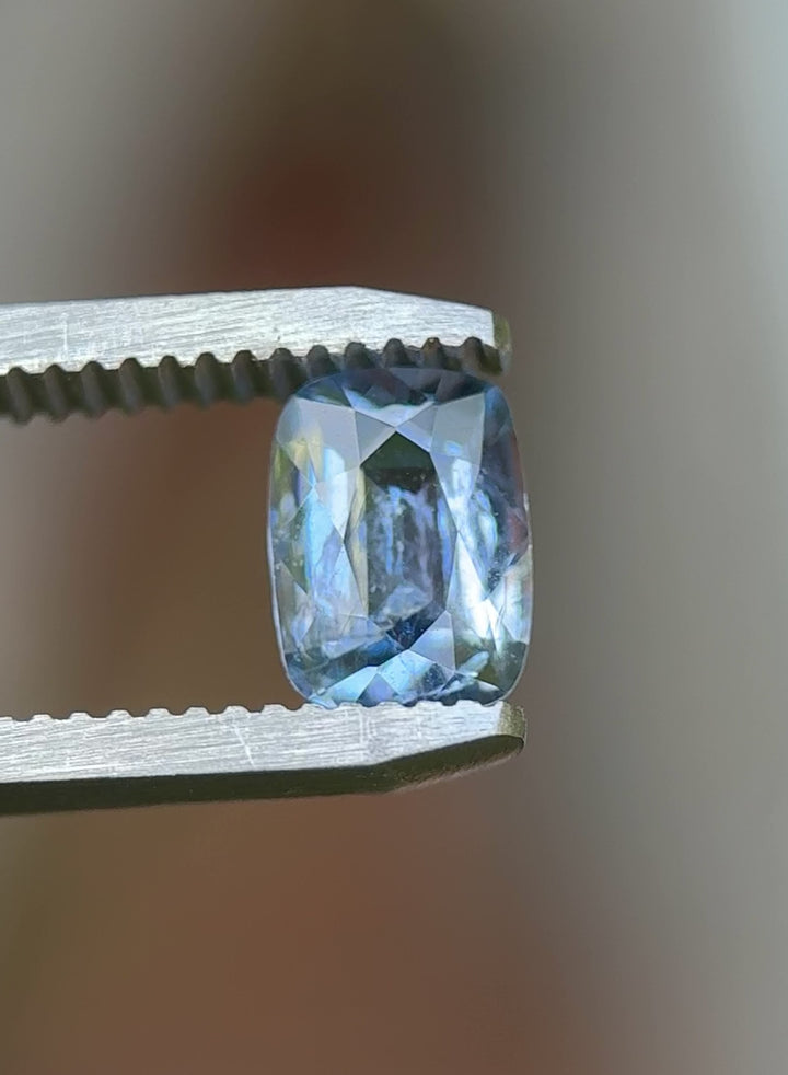 Rotating close-up of a 1.33 carat icy periwinkle blue sapphire in natural daylight, unheated elongated cushion cut from Sri Lanka