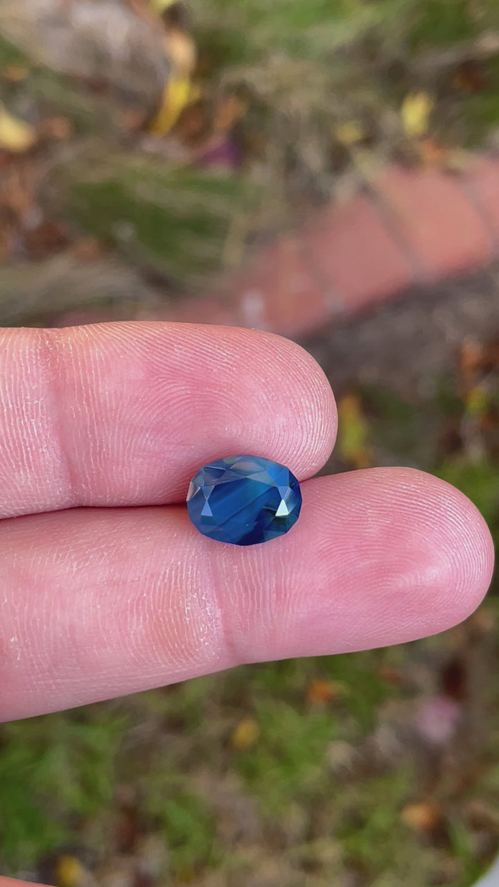 Detailed video view of a 5.23 carat sapphire, displaying its unique blueberry, green, and teal color blend, oval shaped from Gombe, Nigeria.
