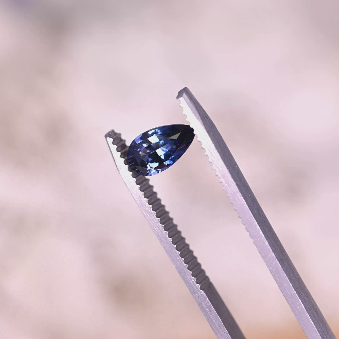 Rotating loose denim blue sapphire from Sakaraha Madagascar showing the sparkle and facet pattern of the mixed brilliant pear cut.