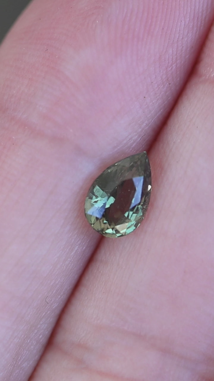 1.016ct pear cut natural alexandrite shown in hand demonstrating green to red color change.