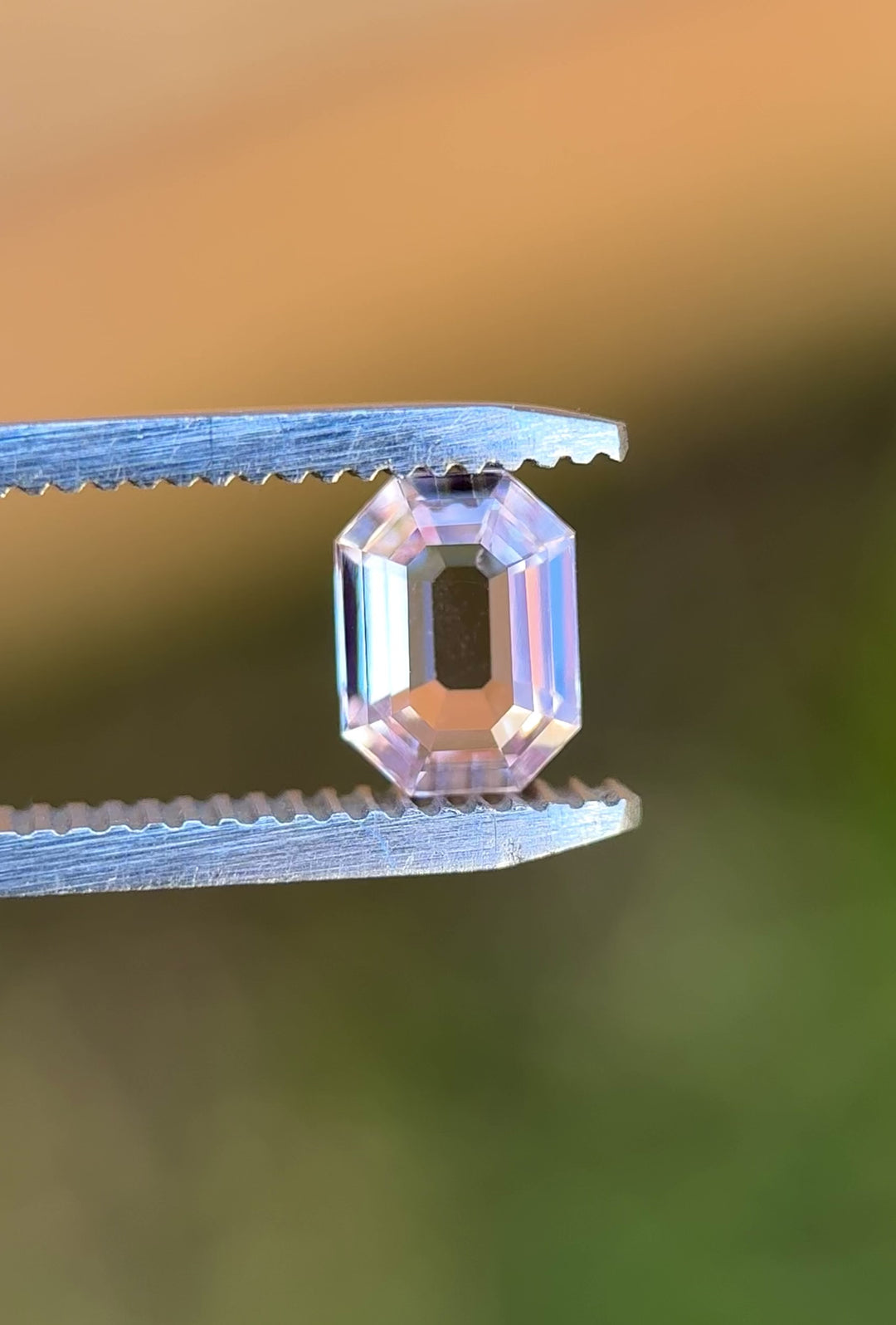 Video of 1.50CT blush pink sapphire rotating in gemstone tweezers, revealing fine step cuts, soft pastel reflections, and clarity of the precision antique emerald cut, unheated sapphire from Sakaraha, Madagascar.