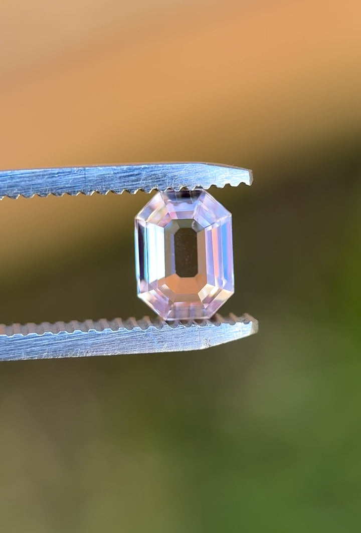 Video of 1.50CT blush pink sapphire rotating in gemstone tweezers, revealing fine step cuts, soft pastel reflections, and clarity of the precision antique emerald cut, unheated sapphire from Sakaraha, Madagascar.
