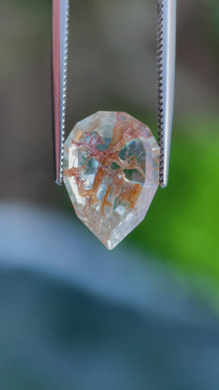 This mesmerizing Hyalite Opal weighs 4.18 carats and features a step-cut pear shape. Its unique mix of clear, orange, and brown hues comes to life with its natural fluorescence, making it a true collector’s gem.
