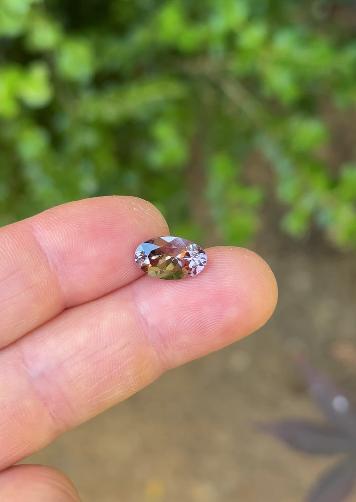 Close-up video of Moval cut Tanzanite rotating under natural light, highlighting reddish orange sparkle and faceting