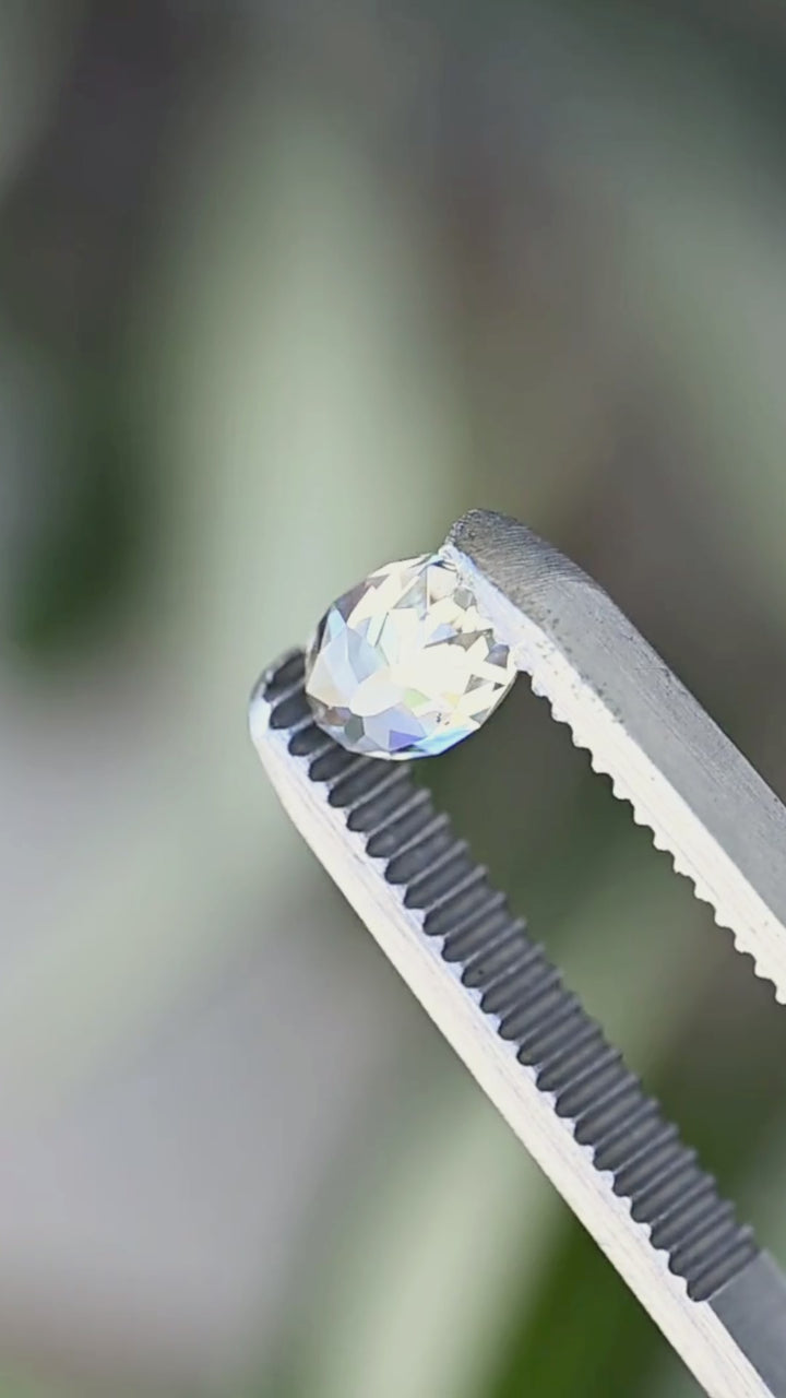 1.09 carat untreated oval Mughal cut diamond rotated between jeweler’s tweezers, showing the elongated outline, broad facets, open central table and natural inclusions from changing angles.
