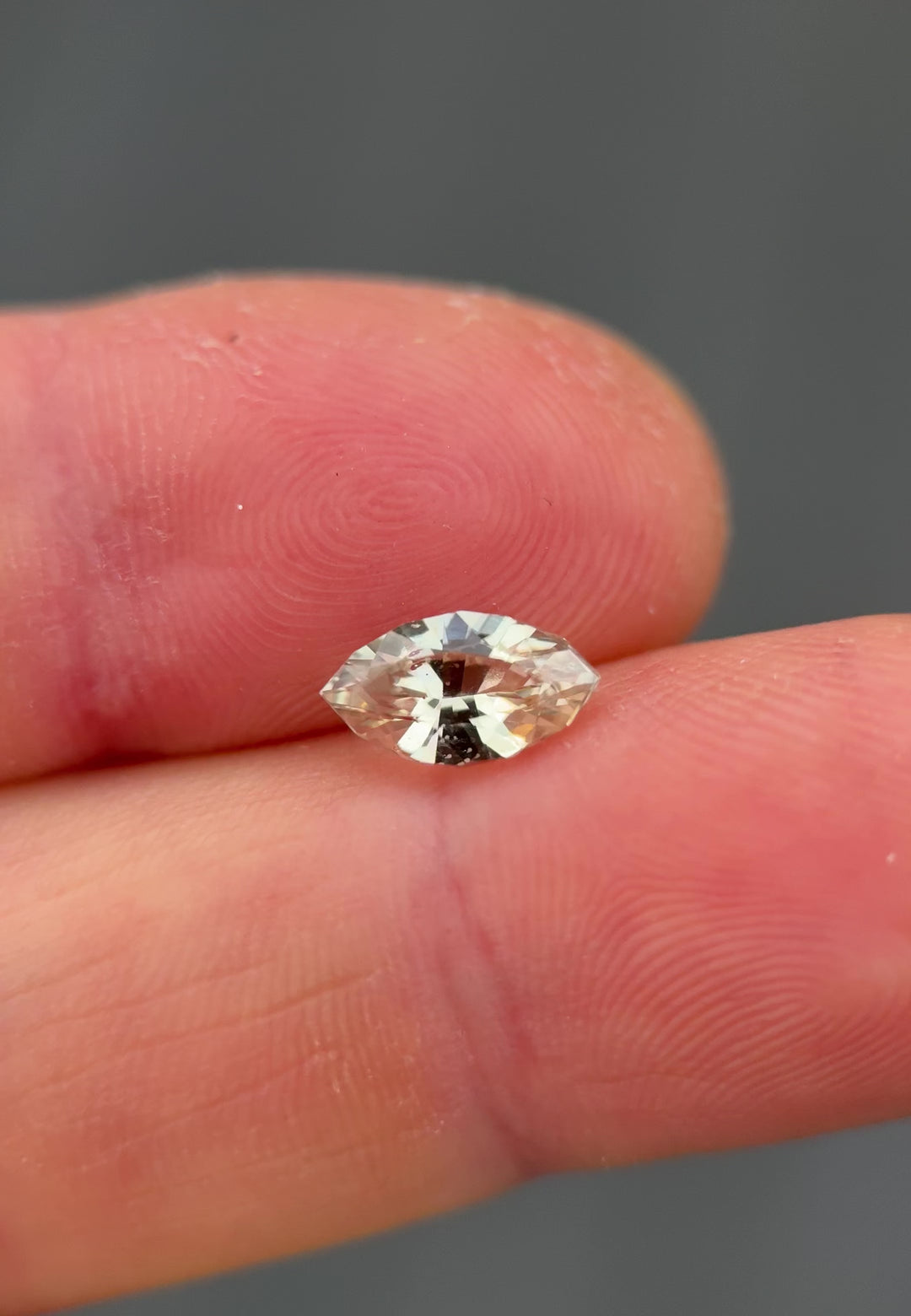 Video of 1.61 carat yellow sapphire on fingertip reflecting natural light, showing vivid golden tones, clarity, and brilliance of the precision marquise mixed cut, untreated sapphire from Sakaraha, Madagascar.