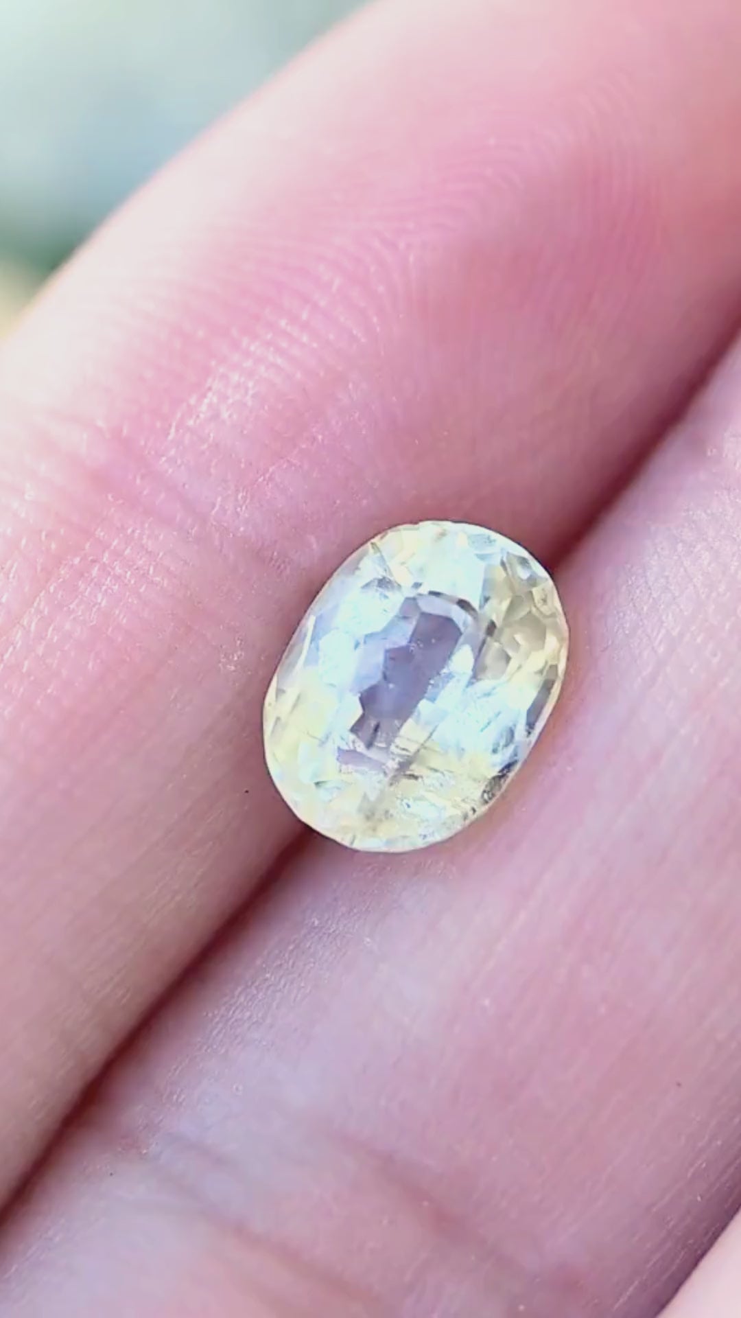 2.37 carat pale yellow tourmaline shown on a hand in natural light, revealing its vintage oval proportions, subtle yellow color, internal inclusions and changing reflections.
