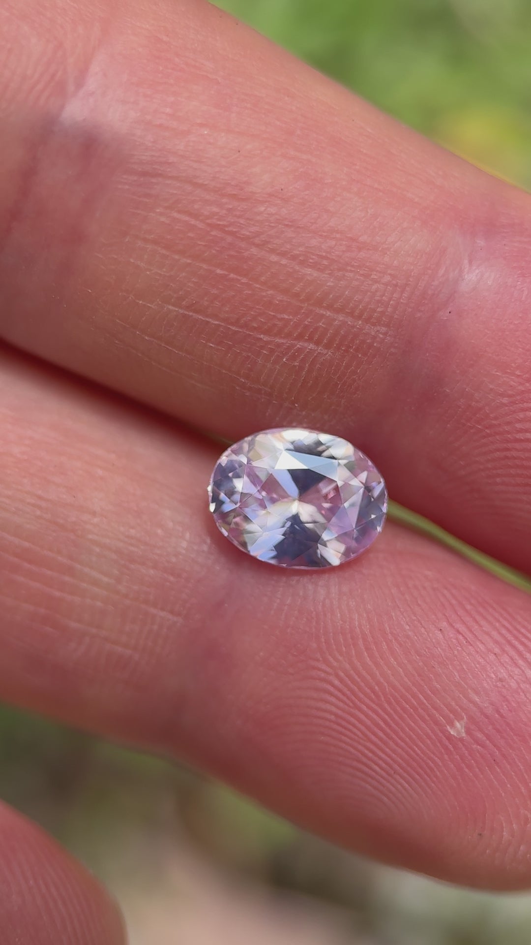 Handheld video of a 2.52-carat Sri Lankan sapphire with opalescent pink hues, featuring a full-view rotation of the oval mix cut stone under soft outdoor lighting.