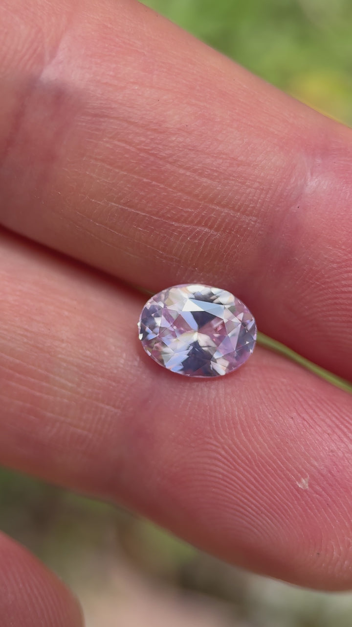 Handheld video of a 2.52-carat Sri Lankan sapphire with opalescent pink hues, featuring a full-view rotation of the oval mix cut stone under soft outdoor lighting.