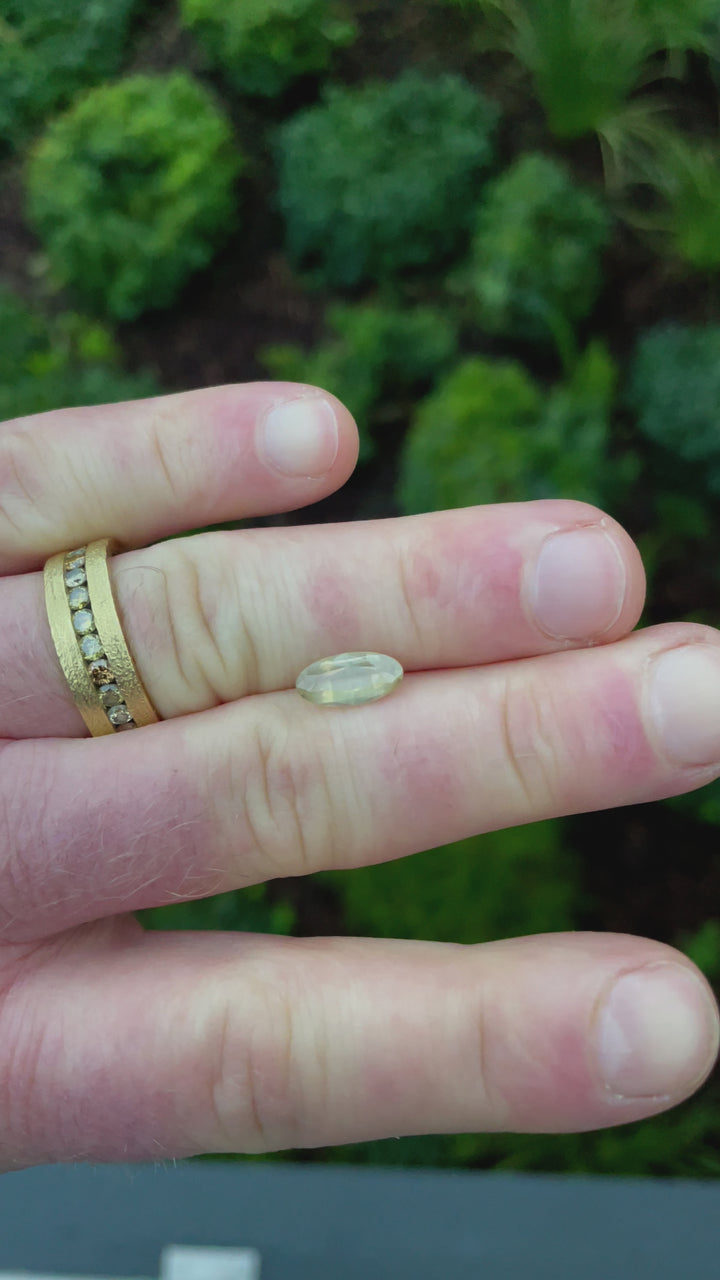 Close-up video showcasing the handling and presentation of a peach, opalescent sapphire, emphasizing its dimension, natural beauty, and the smooth finish of its cut.