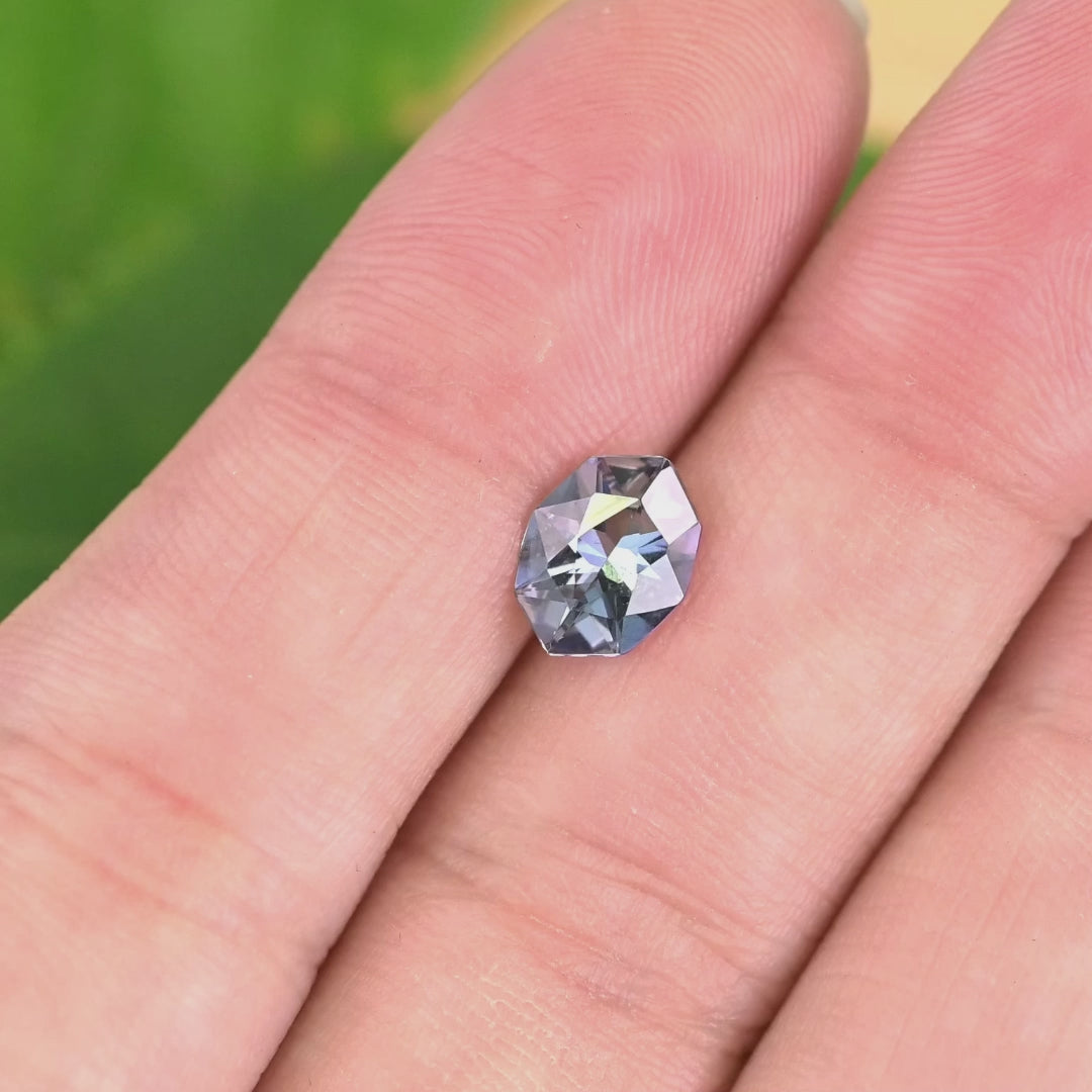 1.27 carat teal blue purple Tanzanite geometric marquise cut in tweezers under natural light, showcasing sharp angular faceting, symmetry and custom jewelry sparkle