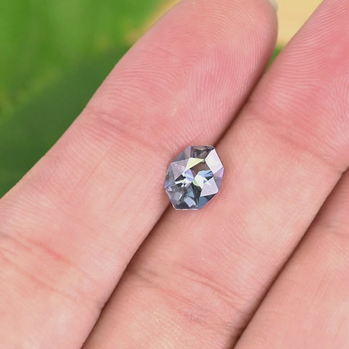1.27 carat teal blue purple Tanzanite geometric marquise cut in tweezers under natural light, showcasing sharp angular faceting, symmetry and custom jewelry sparkle