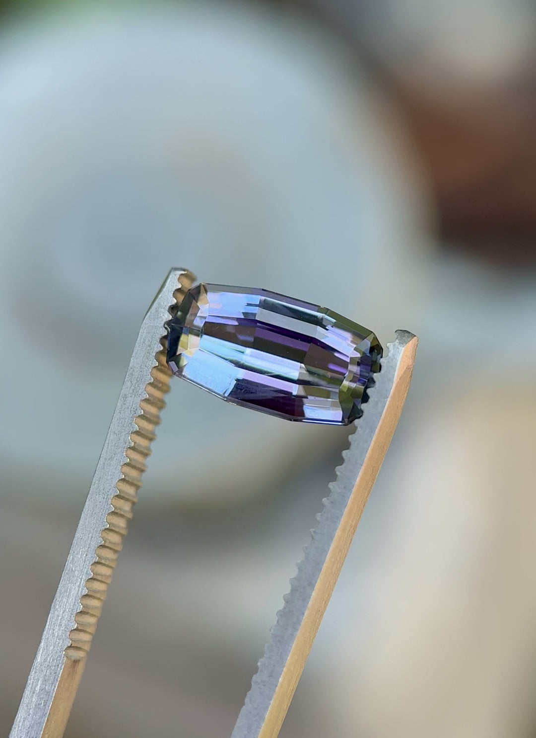 Rotating video of 2.63ct Tanzanite held in tweezers, revealing shifting green, blue, and purple hues in modified emerald cut
