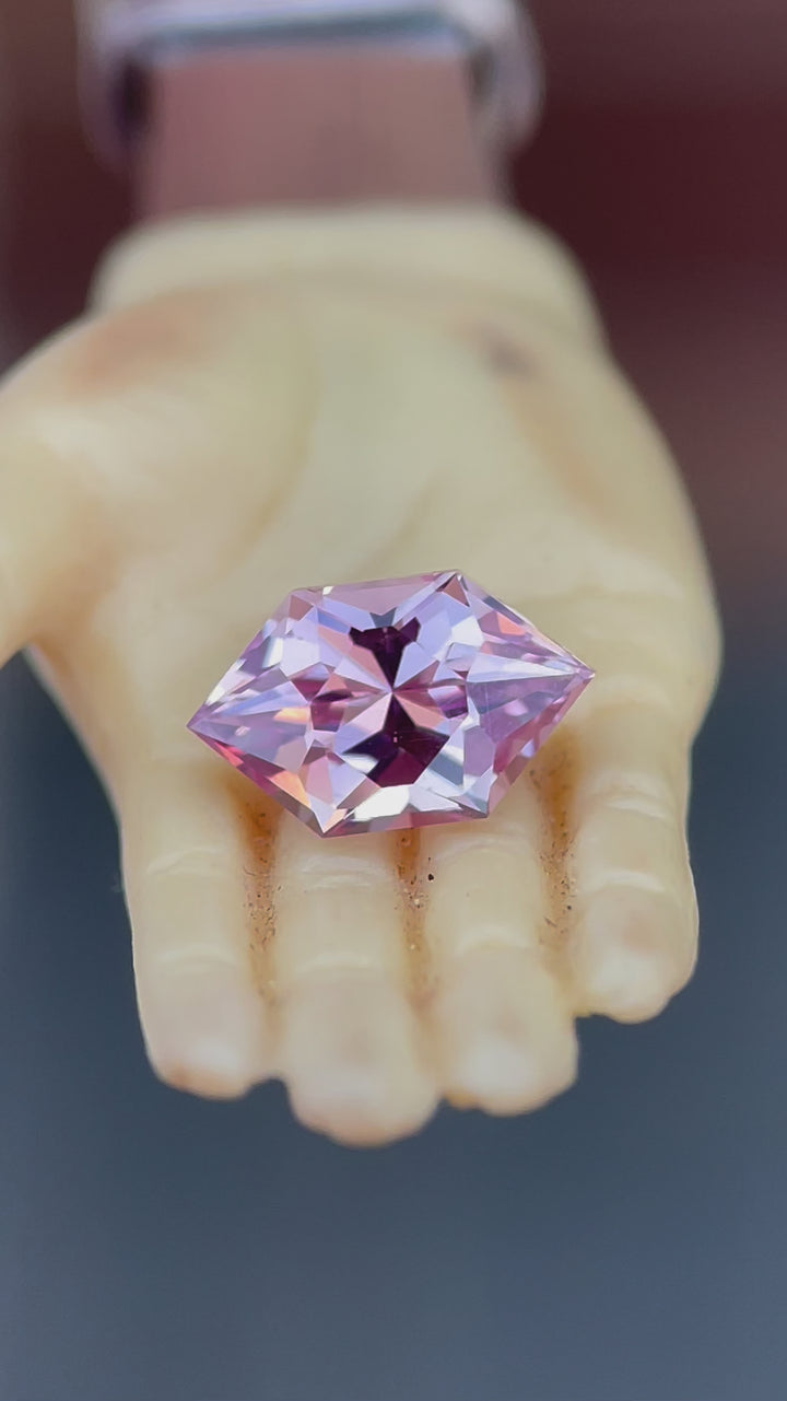 Rotating view of a 1.61 carat blush pink and peach sapphire in a modified brilliant hexagon cut. The video captures the gemstone's sparkle and color shift as light hits its facets, demonstrating its eye-catching brilliance.