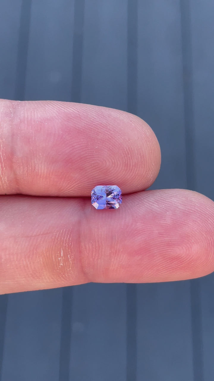 Interactive video displaying the brilliance and radiant cut of a 1.05 carat sapphire in pink and purple, highlighting its dimensions and origin from Sri Lanka