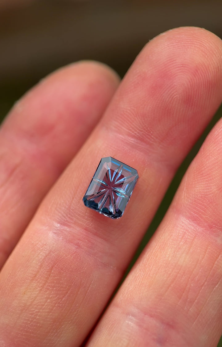 Video of a 2.99 carat violet, teal, and blue Tanzanite from Merelani Hills rotating in hand/light, showing the octagonal concave portrait cut and starburst reflections from multiple angles.