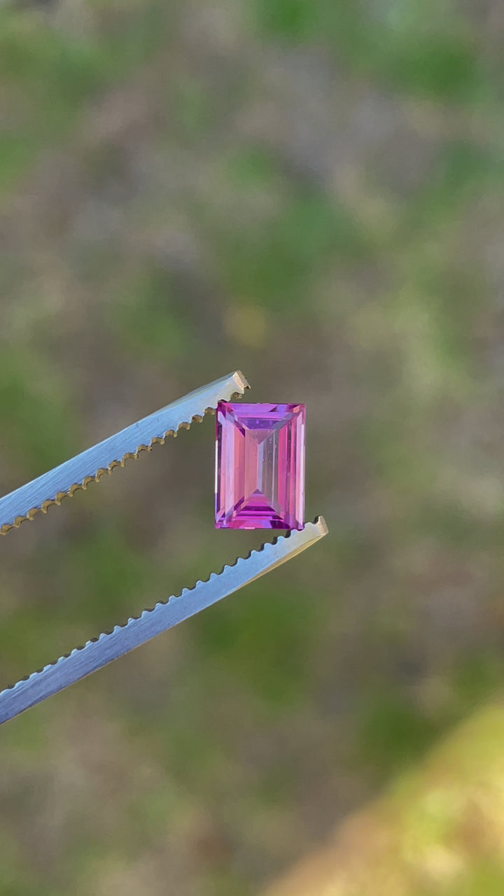 Detailed video presentation of a 1.10 carat emerald cut sapphire, highlighting its deep mulberry, pink, and purple hues and flawless craftsmanship.