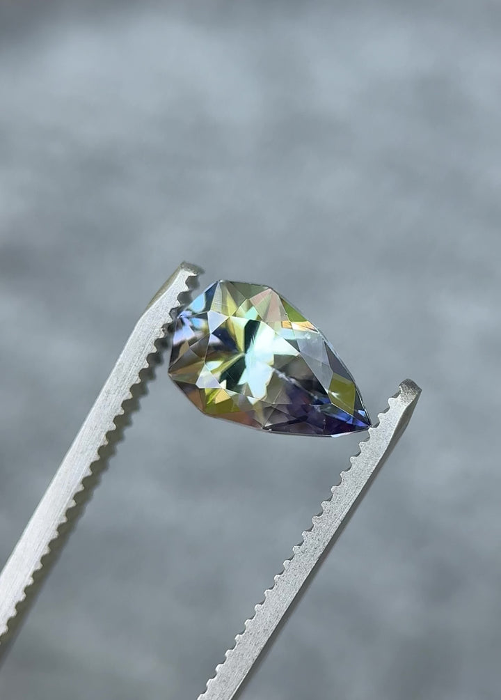 Close-up rotating view of Merelani Hills Tanzanite with teal, purple, and yellow sparkle – 2.46-carat geometric pear cut, unheated gem