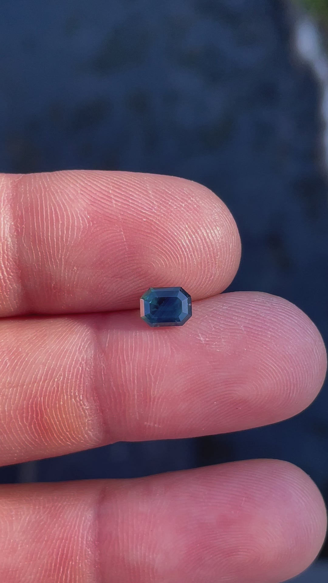 Handheld video of a natural Nigerian sapphire, weighing 1.40 carats, with a refined step-cut and vibrant teal-blue brilliance.