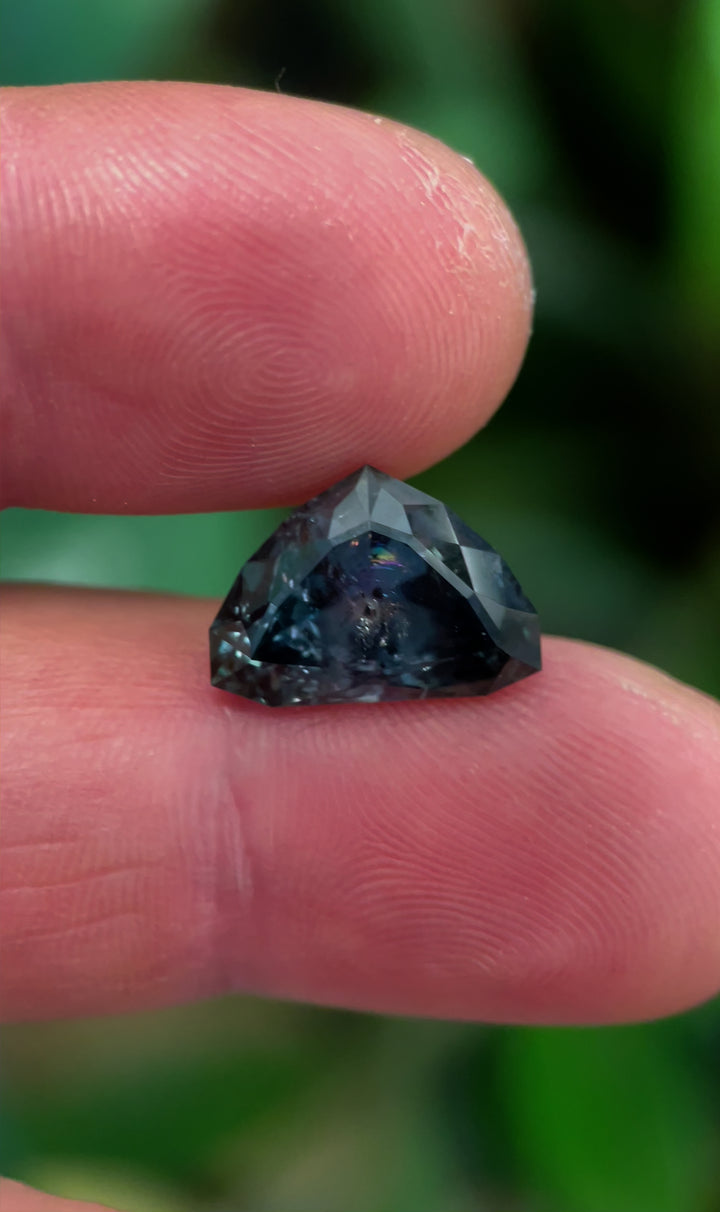 A mesmerizing display of a 7.06-carat Montana sapphire, highlighting its bluish-green hues shifting to gray-purple under different lighting conditions.