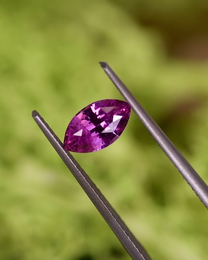 Video of 1.24CT pink sapphire rotating in gemstone tweezers, capturing flashes of vivid pink brilliance and the detailed faceting of the marquise brilliant cut, natural unheated sapphire from Sakaraha, Madagascar.