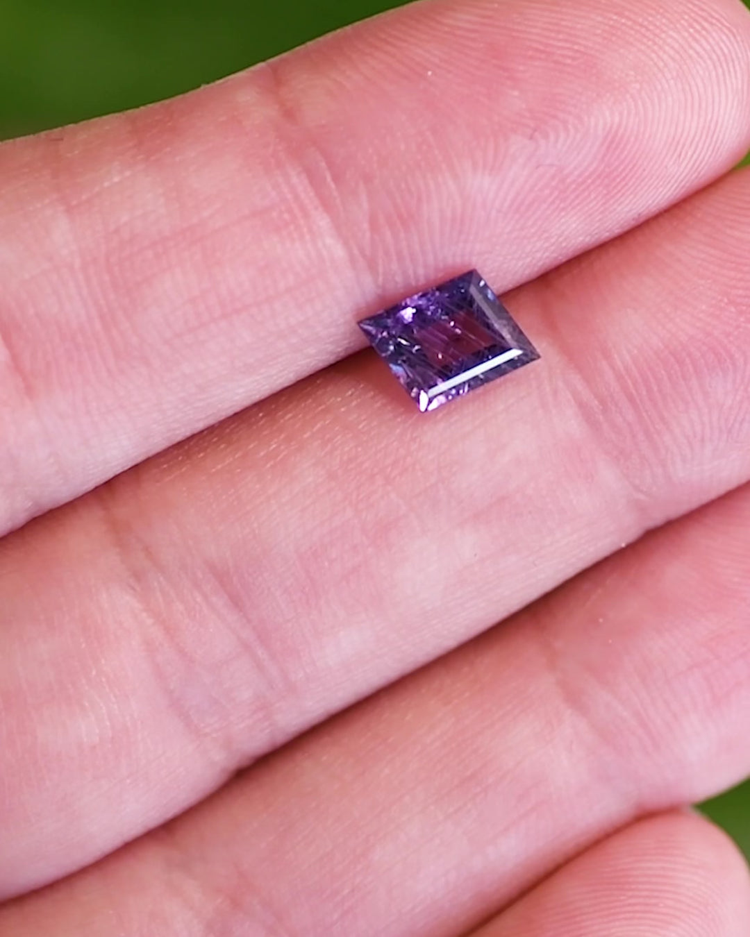 Close-up video of 1.40 carat purple sapphire resting on fingertips, revealing the gemstone’s brilliance, natural inclusions, and rich violet tones of the untreated rhombus step cut sapphire from Tanzania.