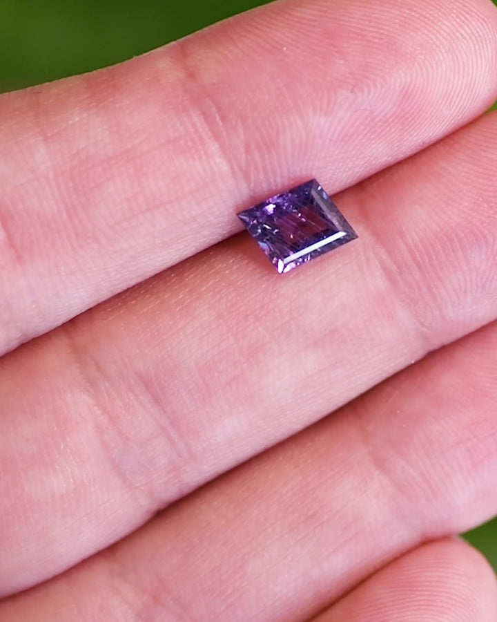 Close-up video of 1.40 carat purple sapphire resting on fingertips, revealing the gemstone’s brilliance, natural inclusions, and rich violet tones of the untreated rhombus step cut sapphire from Tanzania.