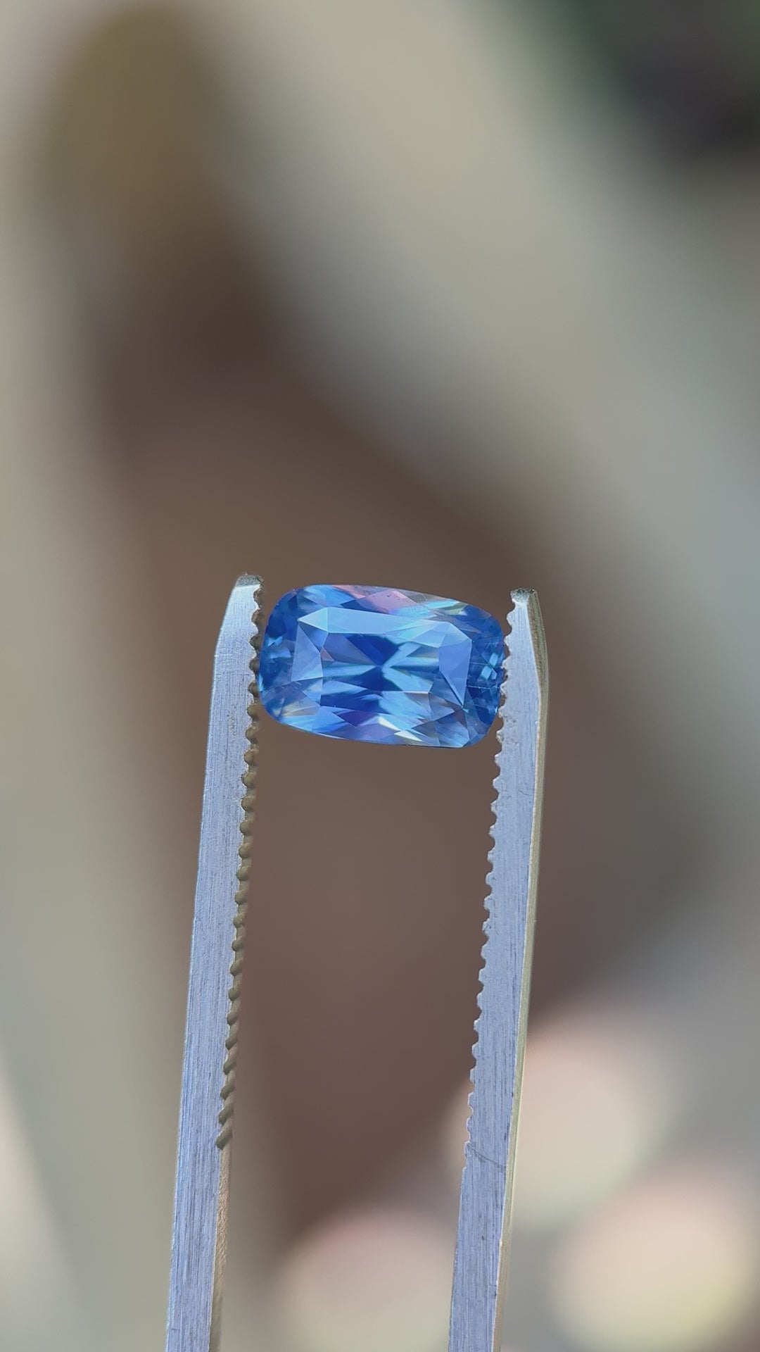 Rotating 2.30 carat cornflower blue sapphire under natural daylight, showing brilliance, elongated cushion mixed cut facets, and untreated Madagascar color performance.