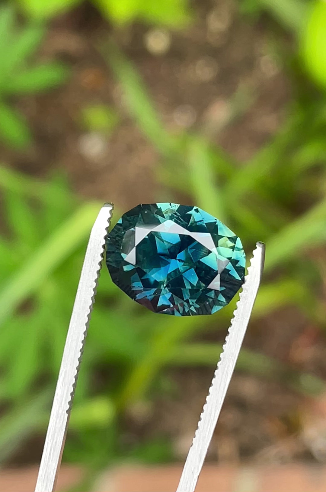 Rotating video of a 7.75-carat oval sapphire from Gombe, Nigeria, showing teal and blue brilliance and faceting under natural light.
