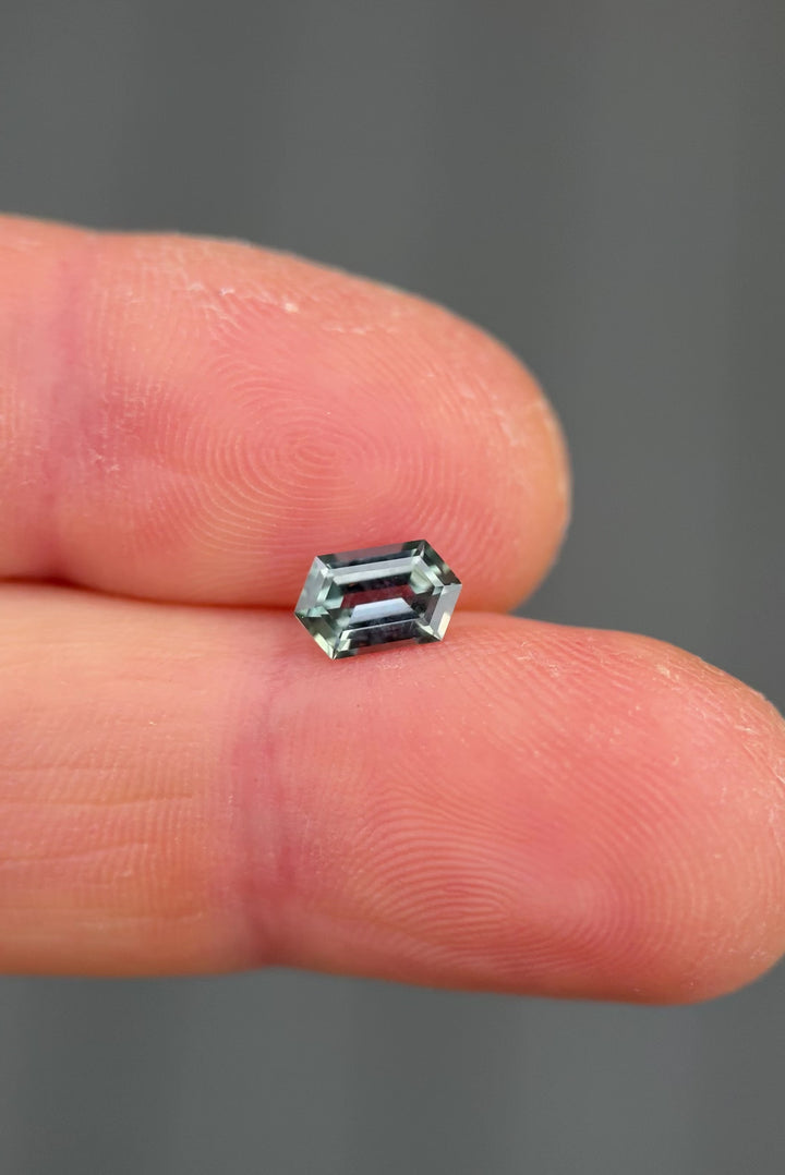 Rotating color shift Montana sapphire video showing elongated hexagon step cut facets as the gemstone transitions from light seafoam green to soft purple under natural light movement