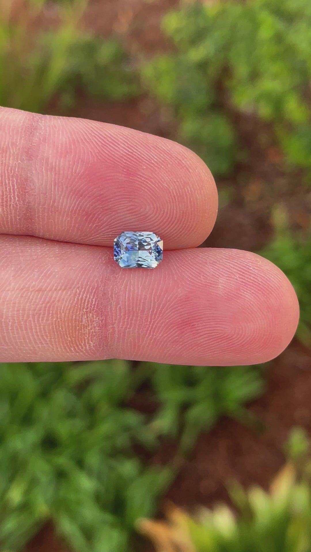 A 360-degree video showcasing the brilliance of a radiant-cut parti sapphire. Weighing 1.52 carats, the gemstone displays a striking combination of blue, yellow, teal, and green tones.