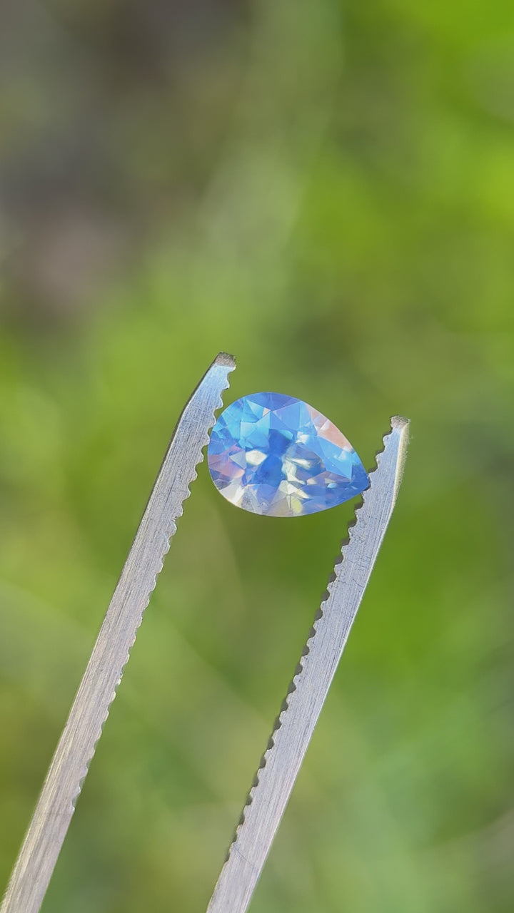 Rotating loose 1.11 carat opalescent cornflower blue sapphire from Nigeria showing the brilliance and light play of the precision brilliant pear cut.