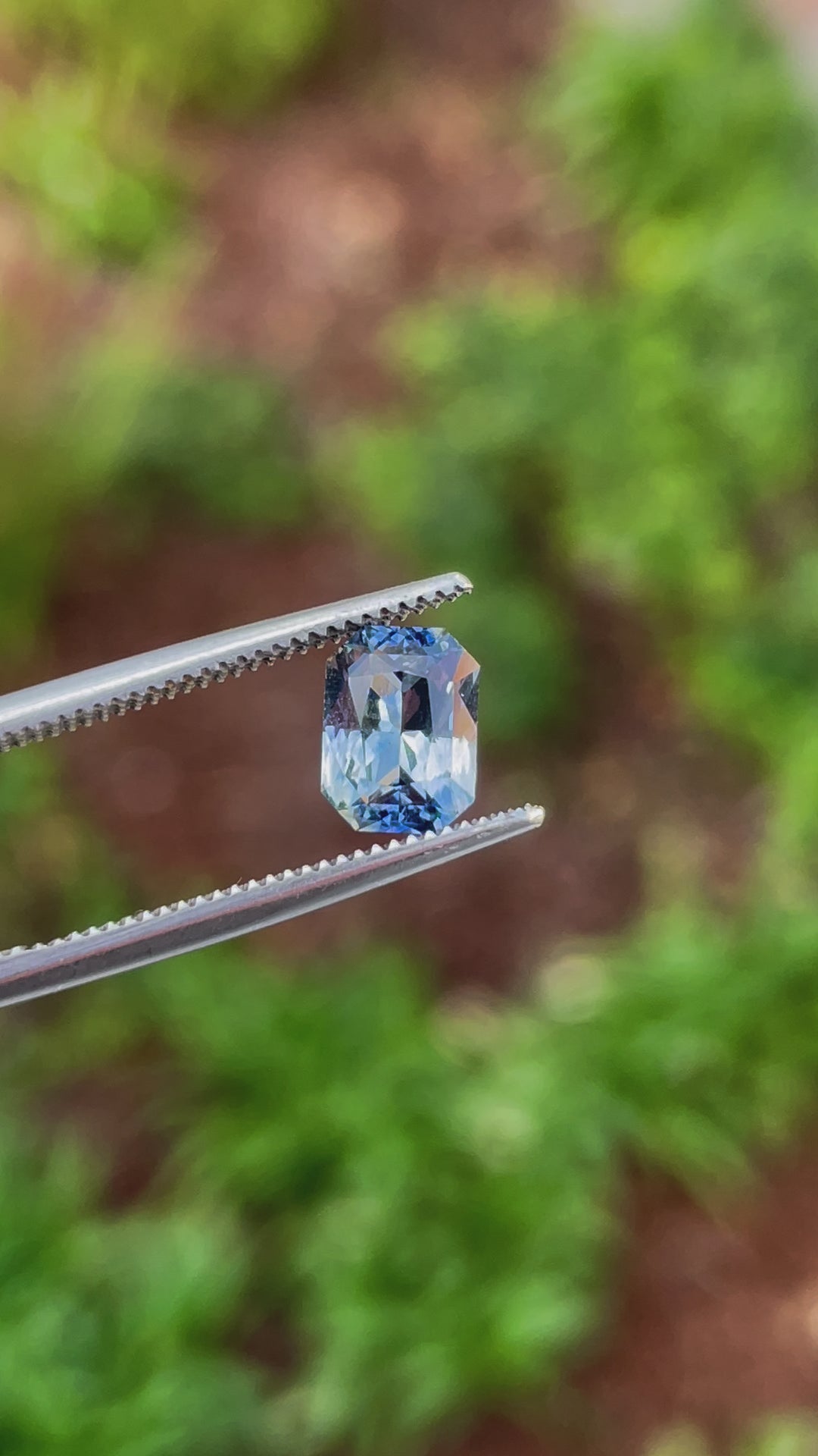 A close-up video of a 1.52-carat radiant-cut parti sapphire, highlighting its dynamic color shift between blue, yellow, teal, and green under natural lighting conditions.