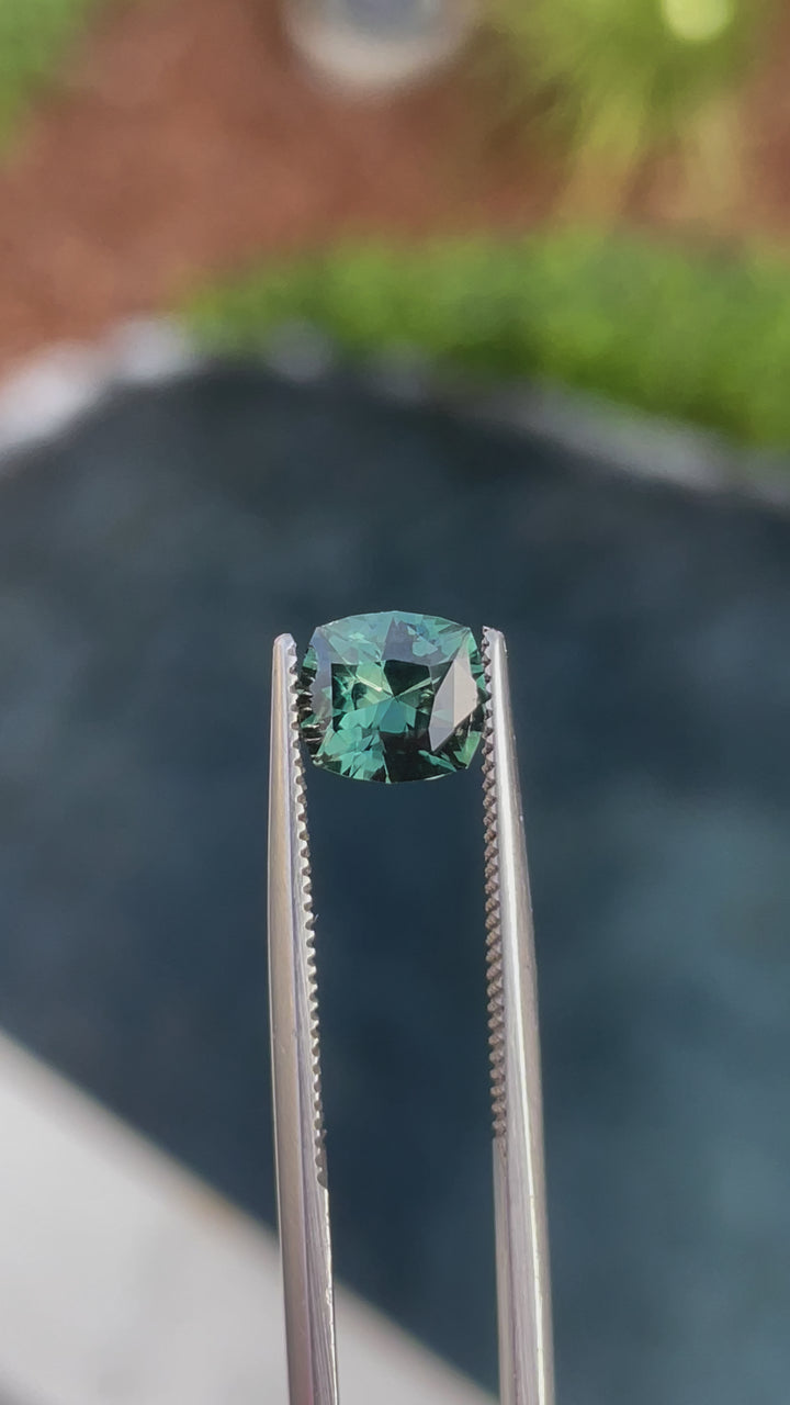 Video showcasing a 1.55-carat blue-green sapphire from Madagascar, rotating to display its fancy mixed cut and vibrant colors. The gemstone's untreated nature and intricate cut are emphasized, providing a comprehensive view of its facets and color dynamics.