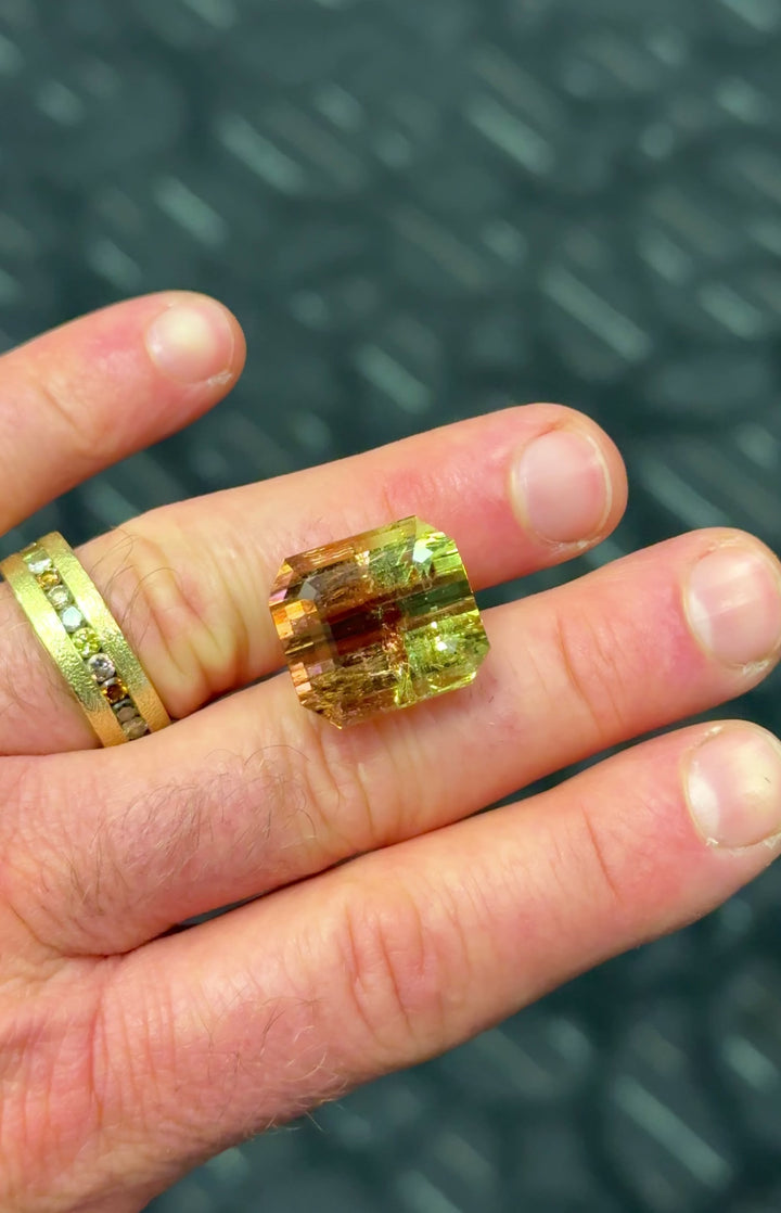 Close up video of 43.06 carat multi color tourmaline turning in natural light, emerald cut facets highlighting peach pink and green zoning