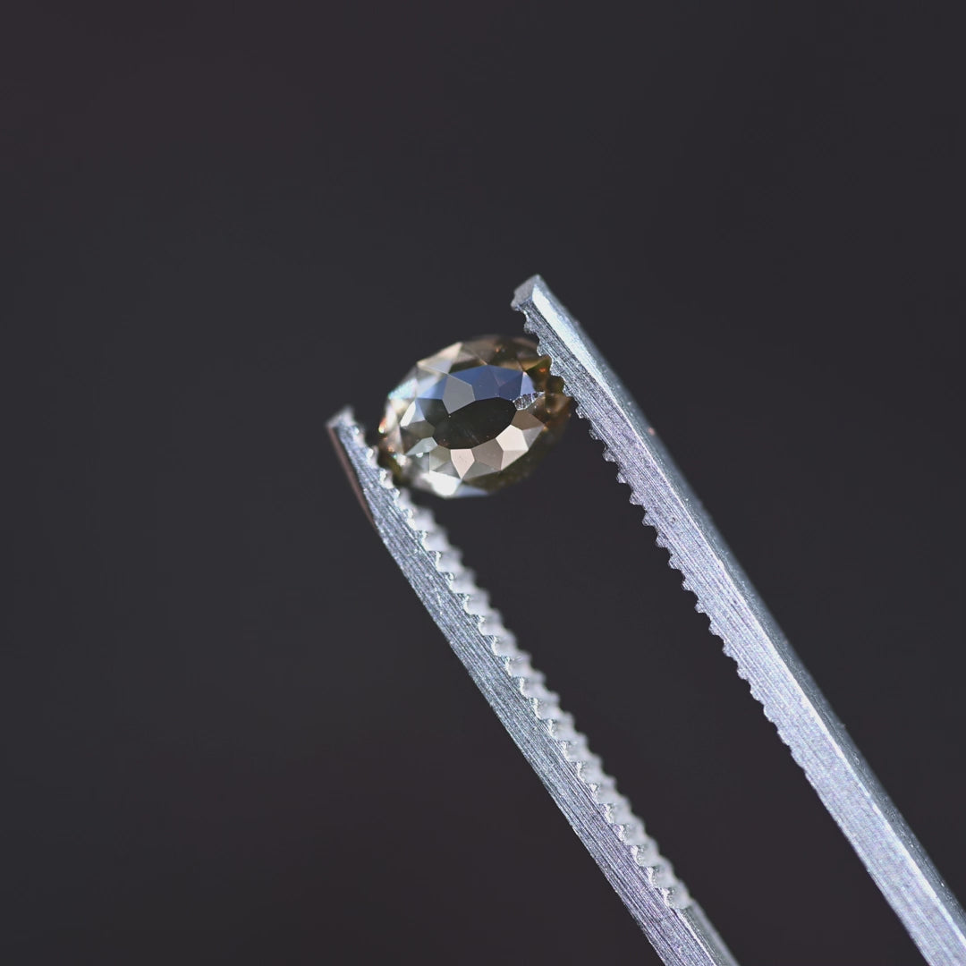 Loose fancy brown champagne Mughal cut diamond from South Africa rotating in tweezers, highlighting its symmetrical faceting and domed profile.