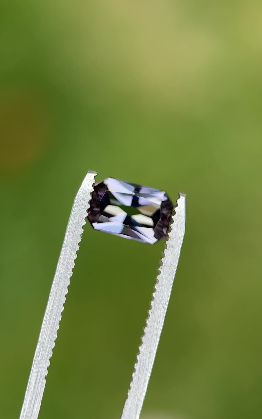 Rotating video of a 1.59-carat radiant cut Tanzanite with mermaid hues of green, blue, and purple held in tweezers