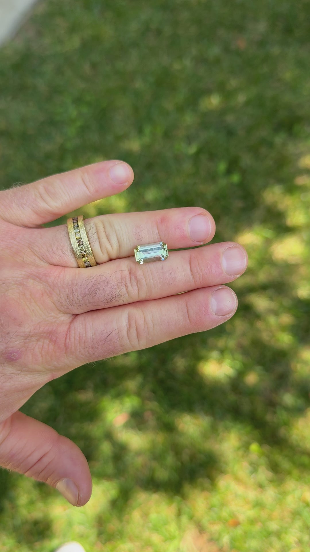 Macro close-up video of natural 4.51CT emerald cut mint green tourmaline gemstone turning in tweezers, revealing step-cut reflections and bright pastel hues, ethically sourced from Congo, Africa.