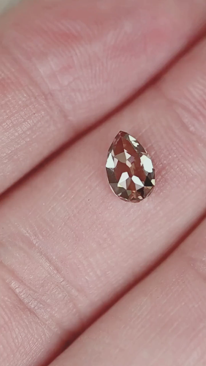 Discover a 1.02ct Fancy Orangish Brown diamond from South Africa, featuring VVS2 clarity and a distinctive Pear Mughal cut. Displayed on the hand for scale, this untreated diamond offers warm cognac and copper coloration with broad geometric faceting. An unusual loose diamond for custom engagement rings, bespoke pendants, and antique-inspired fine jewelry.