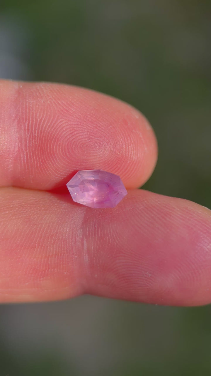 Close-up video of geometric marquise oval sapphire showing pastel pink tones and muted brilliance.