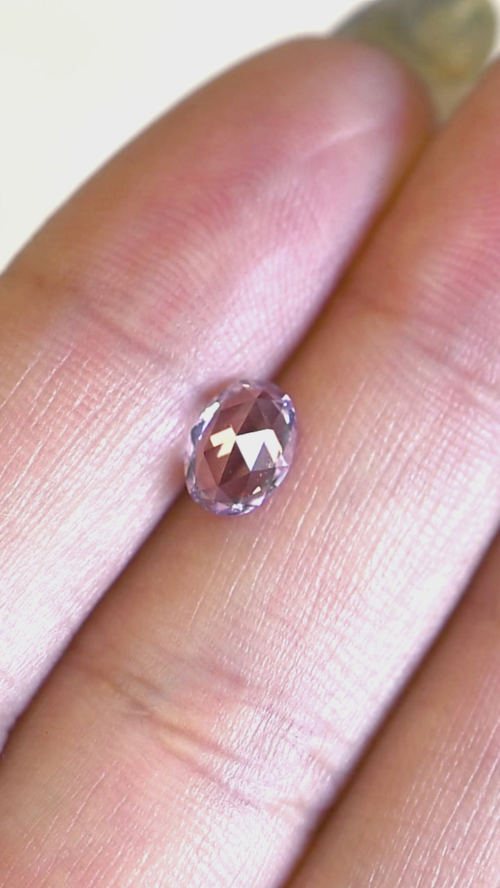 1.21ct opalescent violet purple pink sapphire rotating in hand, revealing soft pastel flashes and balanced oval mix cut brilliance.