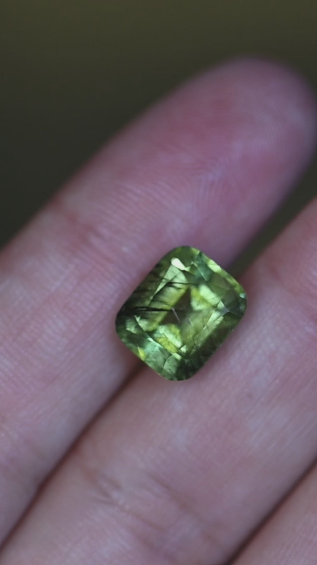 View this natural untreated Pakistan peridot in hand as its serene sage green color, cushion mix cut, and layered crystal inclusions come to life from every angle.