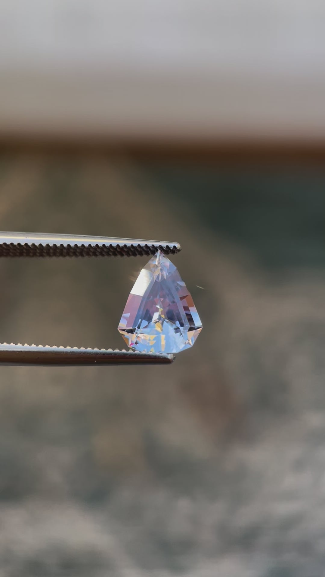 Video of a Custom Modified Shield Cut Sapphire Gemstone Showing Color Shift from Pale Lavender to Pale Blue, Weighing 2.44 Carats, with Dimensions 10.33 x 8.17 x 4.76 mm, Originating from Sri Lanka - No Heat Treatment