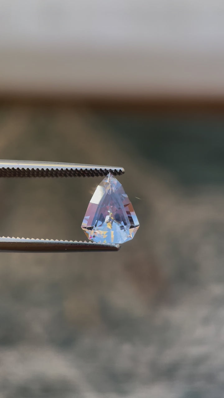 Video of a Custom Modified Shield Cut Sapphire Gemstone Showing Color Shift from Pale Lavender to Pale Blue, Weighing 2.44 Carats, with Dimensions 10.33 x 8.17 x 4.76 mm, Originating from Sri Lanka - No Heat Treatment