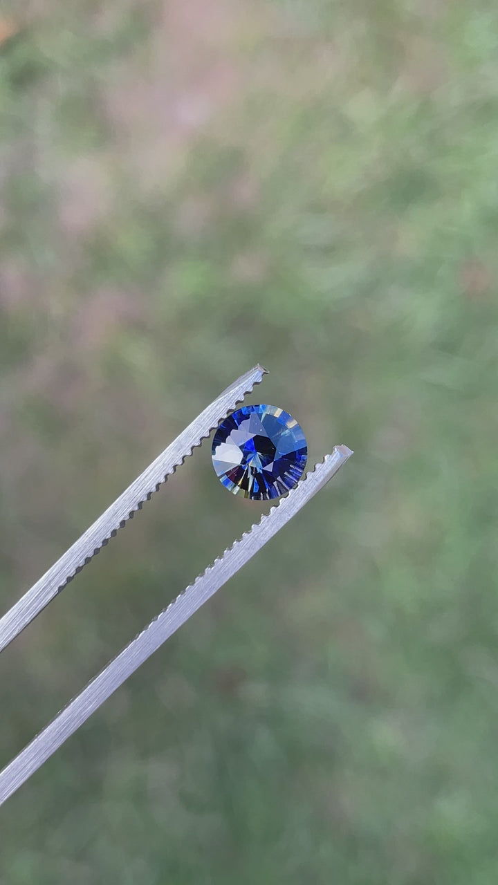 Rotating video of a 1.11-carat round brilliant parti sapphire, highlighting its vivid color zoning and brilliant sparkle from different lighting angles.